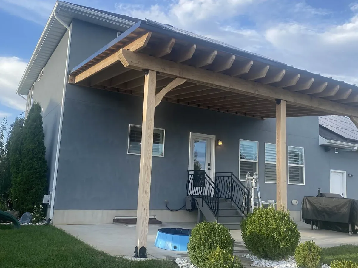 Wood patio cover attached to a stucco house over a concrete patio