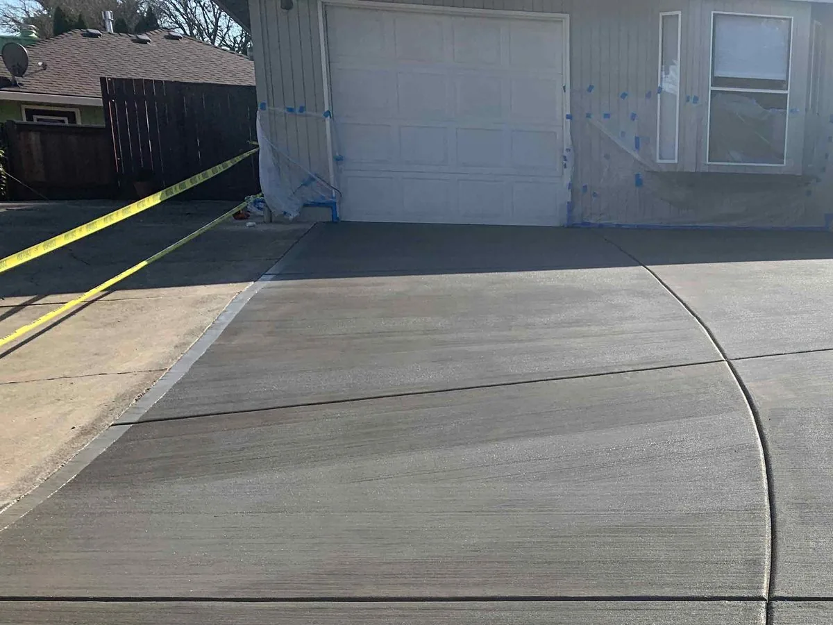 New broom-finished concrete driveway with tooled control joints at a garage