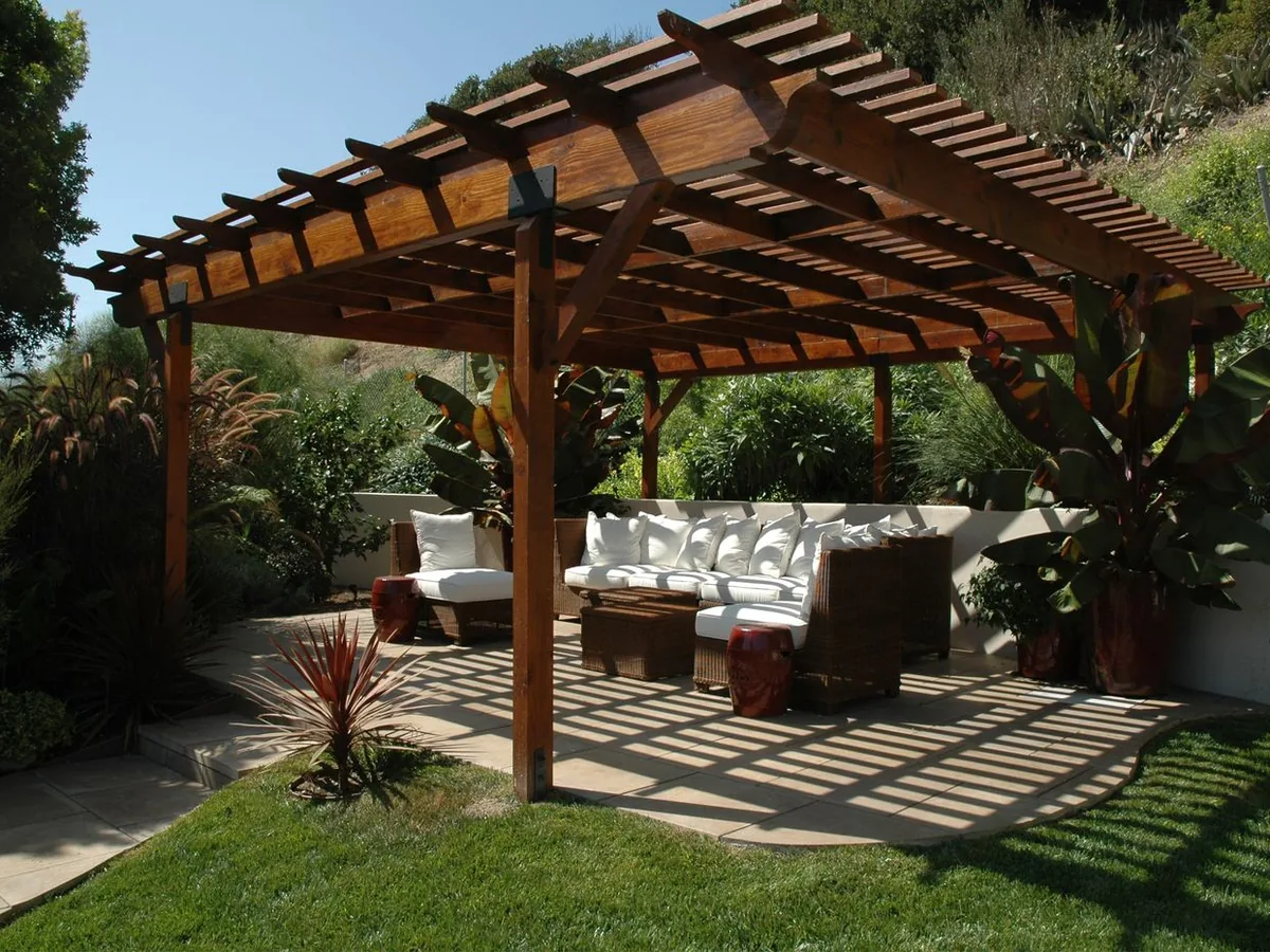 Freestanding wood pergola over a patio with white outdoor sofas