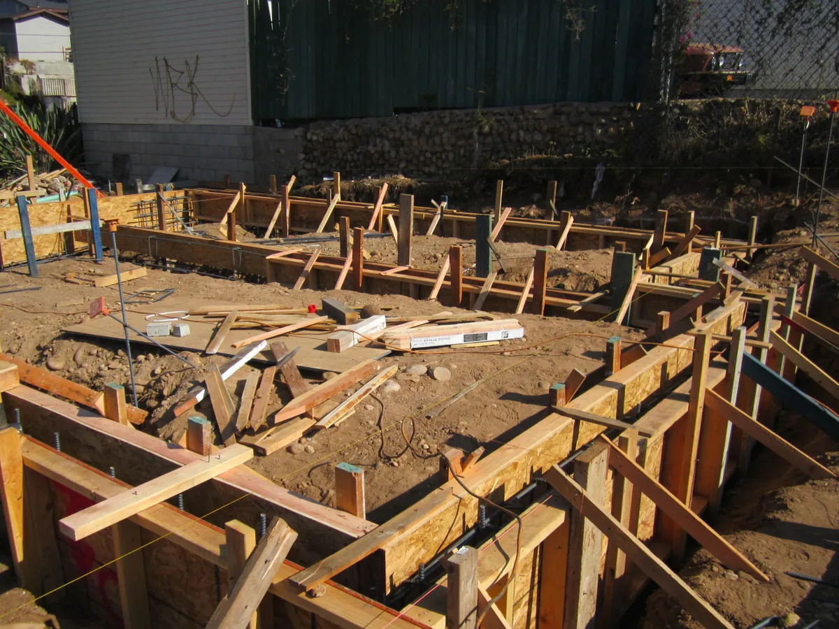 Footing trenches with wood forms and vertical rebar at a hillside site