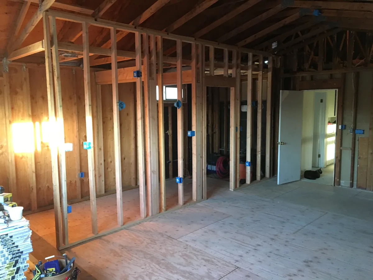 Interior remodel in progress with open stud walls and plywood subfloor