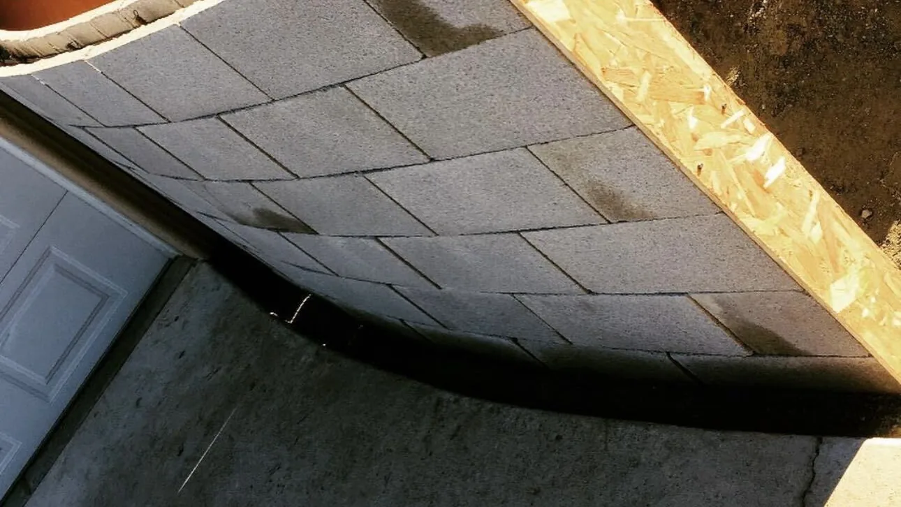 Sweeping band of gray pavers curving along a poured concrete driveway