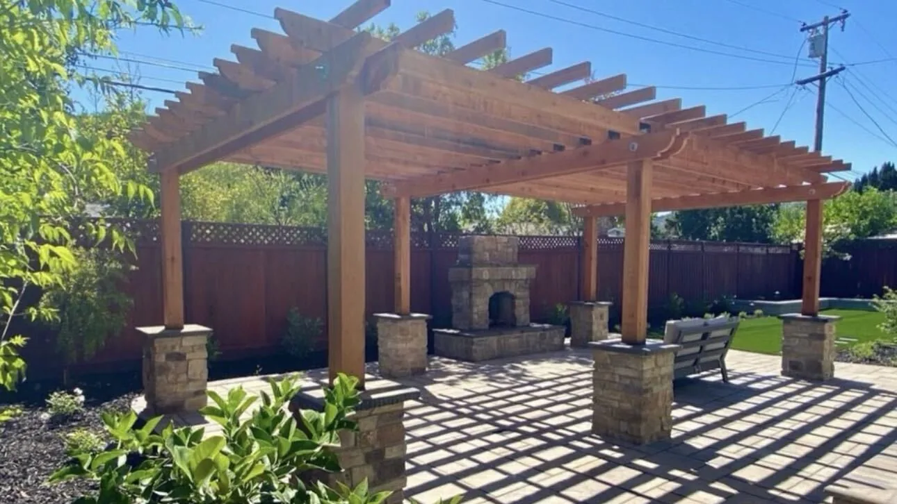 Finished redwood pergola, stone fireplace and paver patio by Aguilar and Sons Construction