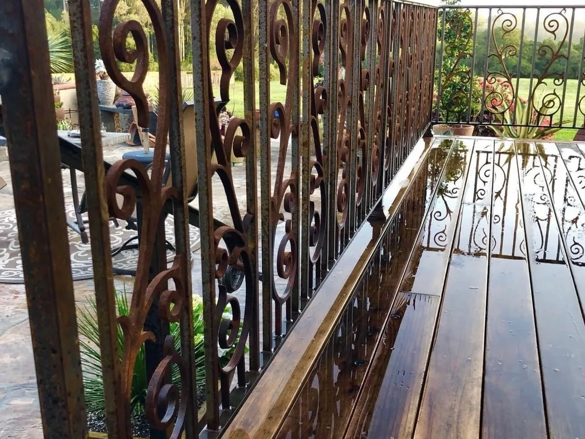 Scrollwork iron railing running along a rain-wet redwood deck