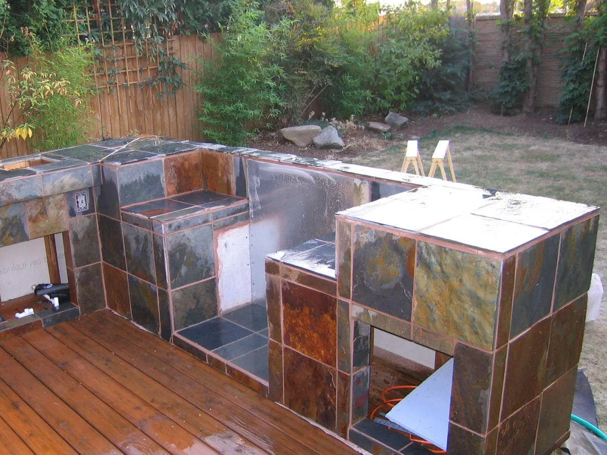 Outdoor kitchen island mid-build with slate tile going onto the frame