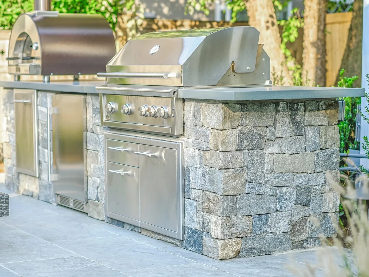 Close view of stone veneer island, stone countertop and built-in grill