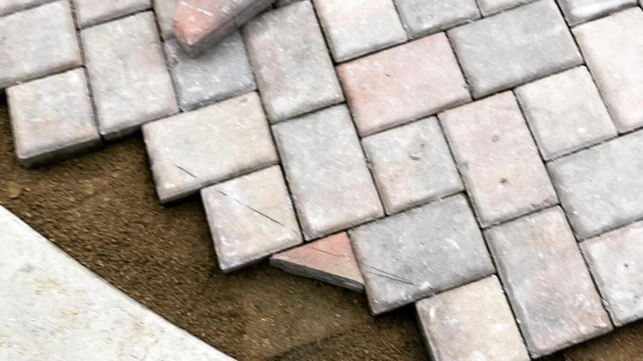 Tumbled pavers laid tight against a curved poured concrete edge